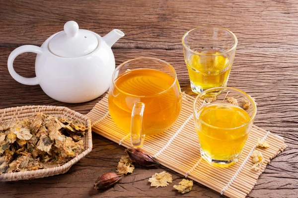 Chrysanthemum tea and Chrysanthemum flowers in a basket on a wood background. Healthy beverage for a drink. Herbs and medical concepts.