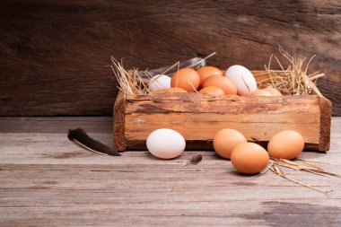 Chicken eggs are laid on the ground and put in a basket on a wooden table on, a rural farm
