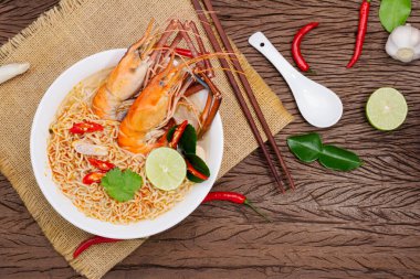 Tom Yum Goong Anında Erişte Ramen - Asya usulü Tayland ve Çinliler baharatlıdır. Tahta bir masaya, deniz ürünleri karidesi, limon, kırmızı biber, sarımsak, galangal, limon otu, kaffir kireç standı..