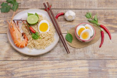 Tom Yum Goong Anında Erişte Ramen - Asya usulü Tayland ve Çinliler baharatlıdır. Tahta bir masaya, deniz ürünleri karidesleri, limon, kırmızı biber, sarımsak, galangal, limon otu, kaffir kireç standı.