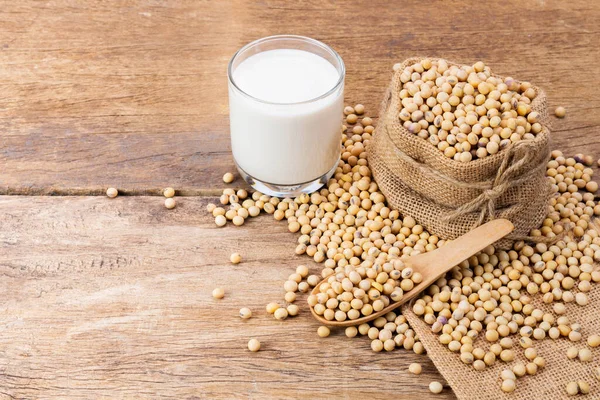 Soy milk in a glass with soybeans on a wooden table organic drink high protein healthy breakfast agricultural produce vegetarian