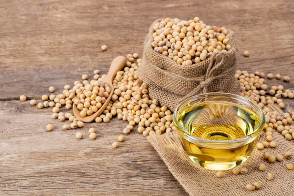 Soybean oil put in a glass cup. and soybeans are on a wooden table