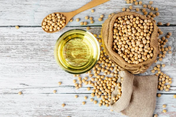 Soybean oil put in a glass cup. and soybeans on a wooden table, natural healthy food - top view