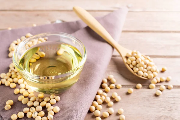 Soybean oil put in a glass cup. and soybeans on a wooden table, natural healthy food - top view