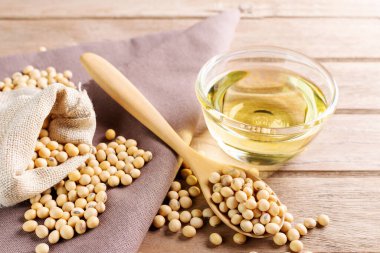 Soya yağı cam bardağa konmuş. ve soya fasulyesi ahşap bir masada, doğal sağlıklı yiyecek - üst görünüm
