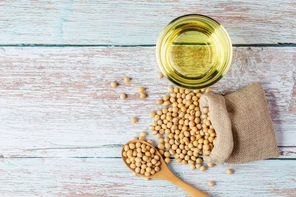Soybean oil put in a glass cup. and soybeans on a wooden table, natural healthy food - top view