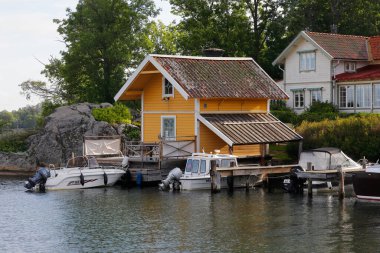 Vaxholm, İsveç - 30 Ağustos 2019: İskeleli tek kişilik deniz kıyısındaki ev manzarası.