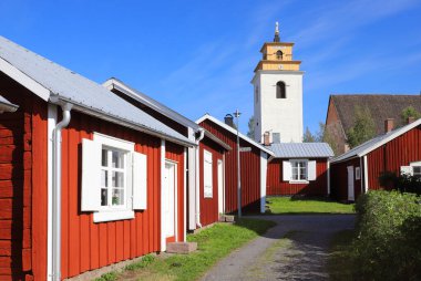 Old red painted cabins in front of the church in the Gammelstad church town. clipart