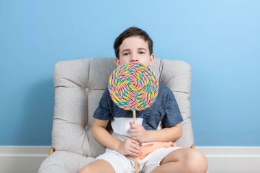 8 yaşında Brezilyalı bir çocuk elinde kocaman renkli bir lolipopla kameraya bakıyor..