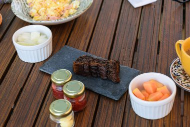 Bir porsiyon papaya, kavun ve çeşitli jölelerin yanında kurabiye keki..