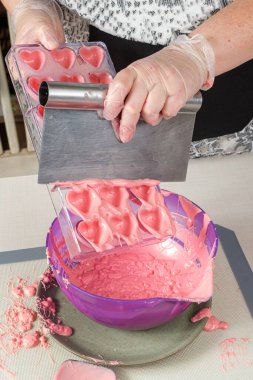 Bir çokkarbonat tavasındaki fazla çilek ganacını temizlemek için bir spatula kullanıyor..