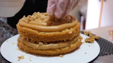 Seçici odaklanma. Şekerlemecinin yaklaşması Dulce de Leche dolgusuna fındık koyması.