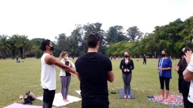 Sao Paulo, Sao Paulo / Brezilya, Temmuz 04, 2021. Yoga pratisyenleri kollarını açıp kapayarak ayakta duruyorlar..