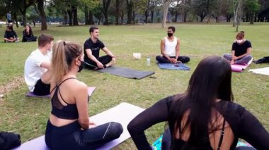Sao Paulo, Sao Paulo / Brezilya, Temmuz 04, 2021. Yoga öğretmeni halka açık bir parkta uygulayıcılarına açıklama yapıyor..