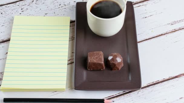 Σημειωματάριο Δίπλα Ένα Φλιτζάνι Καφέ Και Καραμέλες Μαύρη Σοκολάτα — Αρχείο Βίντεο