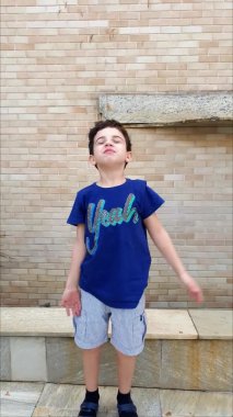 8 year old tossing leaves in the air and having fun on a sunny afternoon_vertical.