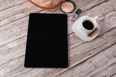 Tablet makyaj çantası, ruj ve kahve fincanı ile çevrili..