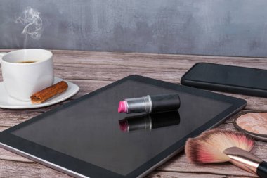 Kahve fincanı, akıllı telefon, pres tozu ve fırçayla çevrili ruj tableti..
