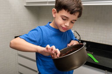 8 yaşında bir çocuk mutfaktan parmağıyla tavadaki tugayları topluyor..