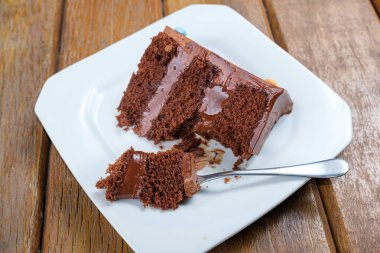 Çikolotalı bir çatalla yarım çikolatalı ganache dolu bir parça çikolatalı pasta..