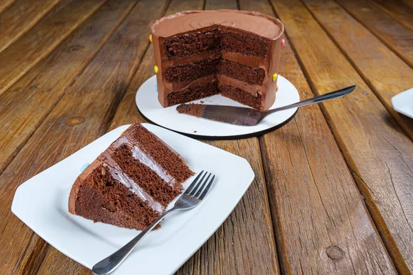 Slice of chocolate cake with filling and semisweet chocolate ganache frosting. Next to the sliced cake_side view.