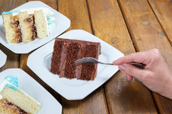 Woman using fork to pick up a piece of chocolate cake with chocolate filling.