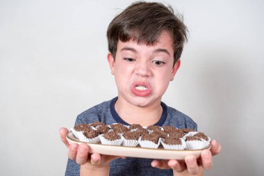 9 yaşındaki Brezilyalı elinde bir tepsi dolusu Brezilya şekeriyle suratını asıyor..