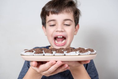 Tepside bir sürü Brezilya şekerlemesi var. Bulanık arka planda, ağzı açık bir çocuk....