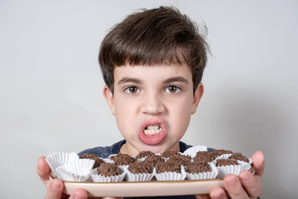 9 yaşında bir çocuk elinde bir tepsi dolusu Brezilya şekerlemesi ve dişlerini gıcırdatıyor..
