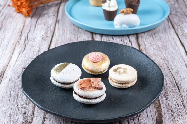 Four macarons, decorated with edible ink and fondant, on a black plate_side view.