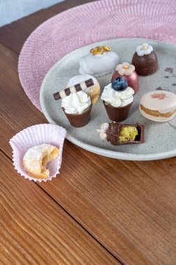 Small chocolate cup with pistachio cream filling next to macaron, truffle and walnut cameo.