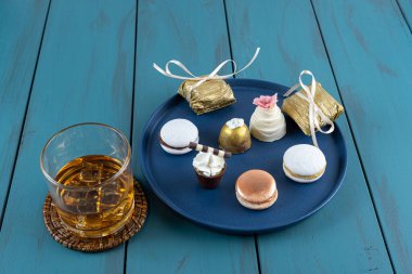 Macaron next to small chocolate glass with whipped cream, walnut cameo, truffle and whiskey glass.