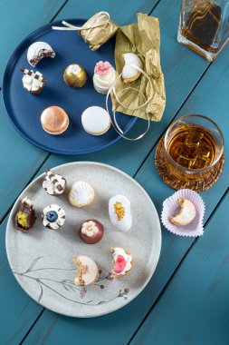 Macaron next to truffle, wedding sweet treat, walnut cameo, bottle and glass of whiskey.
