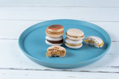 Stack of macarons filled with dulce de leche and chocolate ganache, next to two macarons with bites.