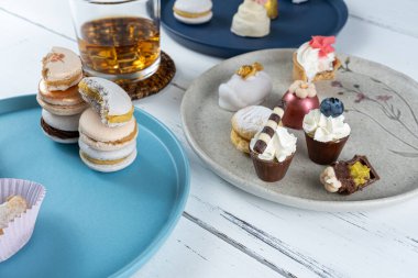 Stacked macarons surrounded by a glass of whiskey and fancy wedding sweets_side view.
