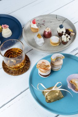 Stacked macarons surrounded by an iced whiskey glass and fancy wedding sweets.