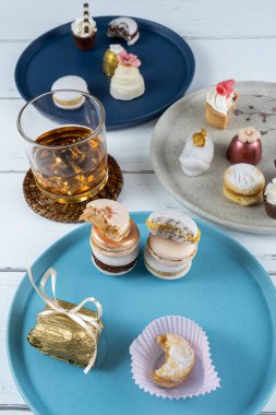 Stacked macarons surrounded by a glass of whiskey and fancy wedding sweets_vertical.