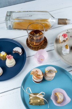 Macarons stacked surrounded by glass and bottle of whiskey and wedding candies.