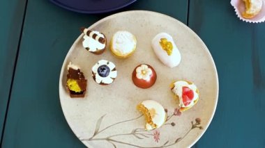 Sophisticated sweets on plates, top view. Glass with whiskey, walnut cameo, chocolate truffle, macaron and wedding sweet treat.