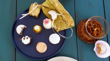 Sophisticated sweets on plates, top view. Glass with whiskey, walnut cameo, macaron, chocolate truffle and wedding sweet treat.