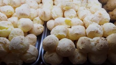 Several Brazilian cheese bread smoking in a Brazilian bakery showcase.