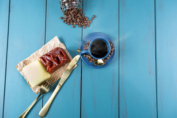 Guava sweet with cheese on a brown paper, surrounded by cutlery, beans and a cup of coffee_top view.