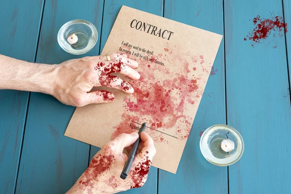 Kanlı eller ve dolma kalemle mumların yanında şeytani kontrat imzalıyorlar..