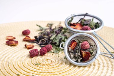 Çay süzgecinde kurutulmuş çay yaprakları ve böğürtlen. Organik, doğal bitki çayı ve kuru böğürtlenli hasır peçete..