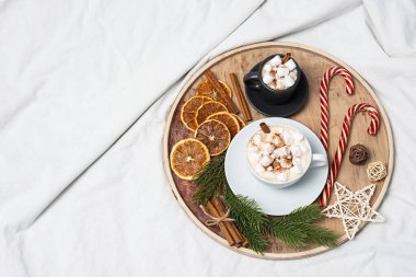 Kış tatili havası. İki kahve fincanı marşmelov, baston şekerler, yatağın üzerinde Noel süsleri. Noel sabahı, kahve zamanı..