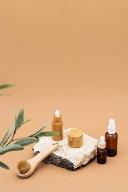 Boş kehribar cam ve bambu esaslı yağ şişeleri, pipette, cam sprey şişesi ve bambu kavanozu doğal taş kürsüde. Organik kaplıca kozmetik güzellik ürünü..