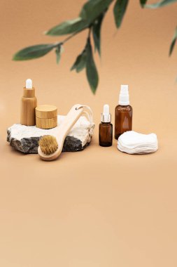 Boş kehribar cam ve bambu esaslı yağ şişeleri, pipette, cam sprey şişesi ve bambu kavanozu doğal taş kürsüde. Organik kaplıca kozmetik güzellik ürünü.