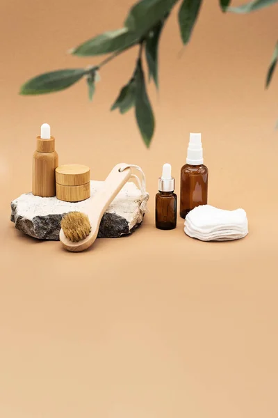 Boş kehribar cam ve bambu esaslı yağ şişeleri, pipette, cam sprey şişesi ve bambu kavanozu doğal taş kürsüde. Organik kaplıca kozmetik güzellik ürünü.