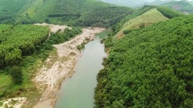 Drone flying above rainforest river surrounded green jungle and mountains. Aerial view of beautiful tropical landscape.