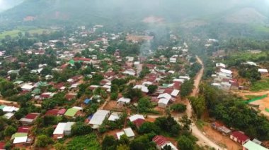 Tropikal Asya dağlarının kırsal manzarası. Yeşil yağmur ormanlarını çevreleyen köyün atmosferik hava çekimi.